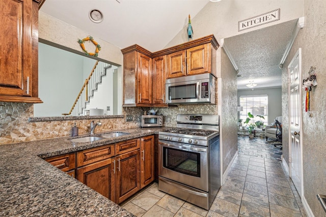 kitchen with backsplash, sink, vaulted ceiling, a textured ceiling, and stainless steel appliances