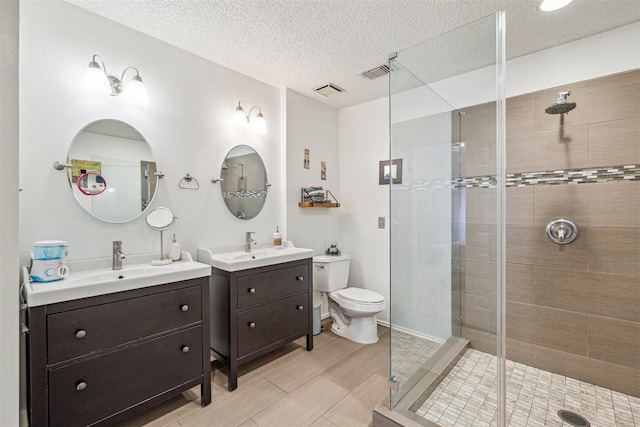 bathroom with a textured ceiling, vanity, an enclosed shower, and toilet