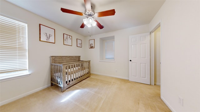 carpeted bedroom featuring a nursery area and ceiling fan