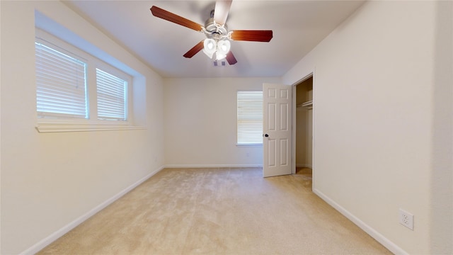 carpeted empty room with a wealth of natural light and ceiling fan