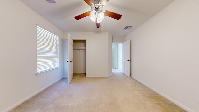 unfurnished bedroom with a closet, light colored carpet, and ceiling fan