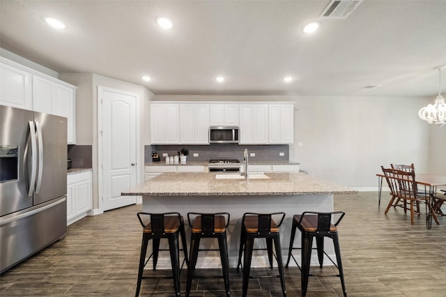 kitchen featuring white cabinetry, stainless steel appliances, and a kitchen island with sink