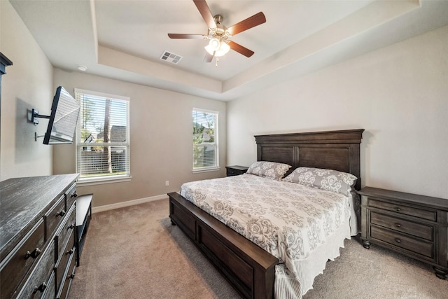 carpeted bedroom featuring ceiling fan and a raised ceiling