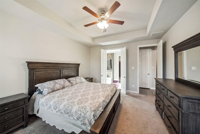 carpeted bedroom with a tray ceiling and ceiling fan