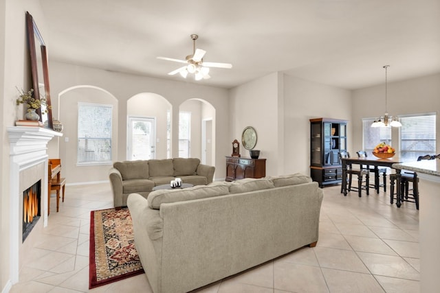 living room featuring ceiling fan with notable chandelier and light tile patterned floors