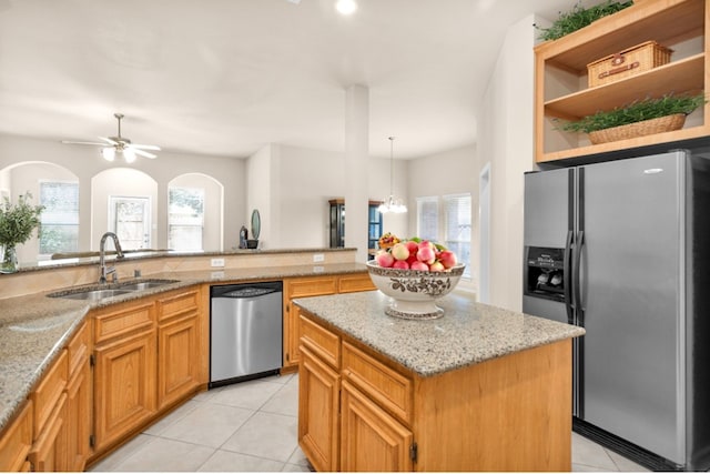 kitchen featuring light stone counters, a center island, stainless steel appliances, and sink