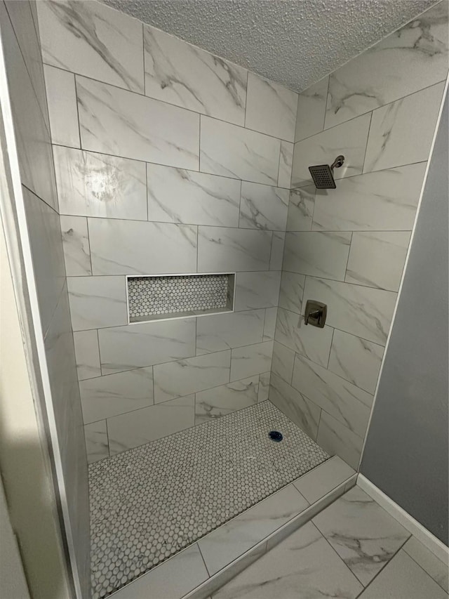 bathroom featuring a textured ceiling and tiled shower