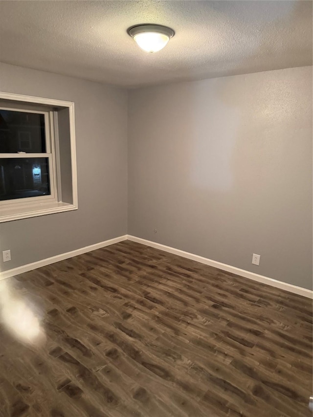 empty room featuring dark wood-type flooring and a textured ceiling