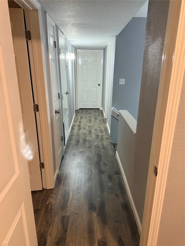 corridor with dark hardwood / wood-style flooring and a textured ceiling