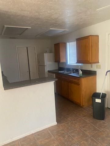 kitchen featuring white fridge, sink, and a textured ceiling