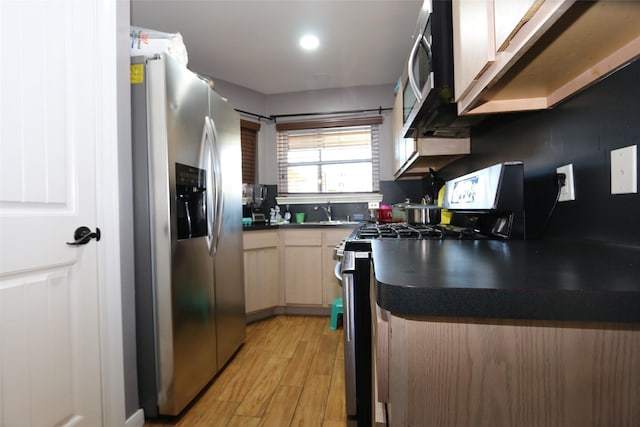 kitchen featuring appliances with stainless steel finishes, light brown cabinets, light hardwood / wood-style floors, and sink