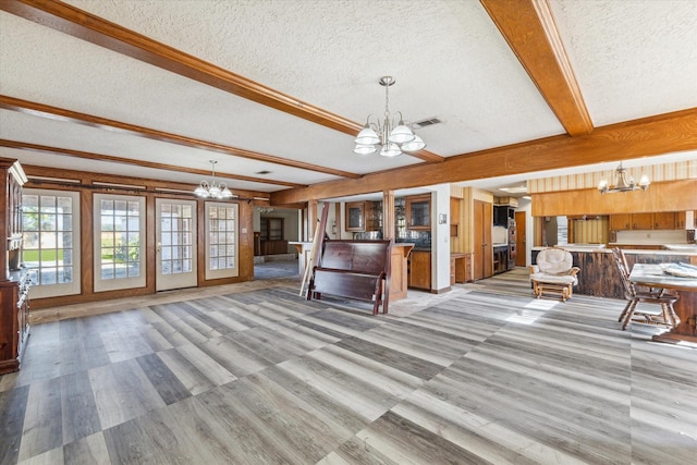 unfurnished living room with beam ceiling, a textured ceiling, and a notable chandelier