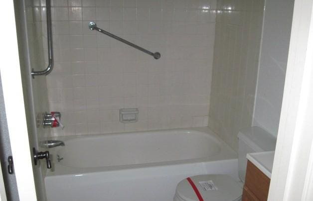 full bathroom featuring tiled shower / bath, vanity, and toilet