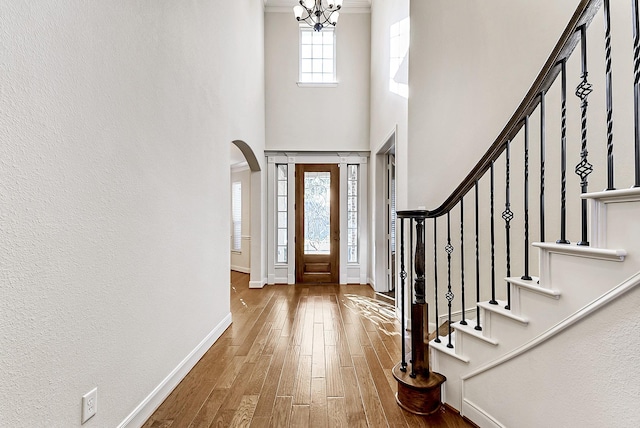 foyer featuring hardwood / wood-style floors, a towering ceiling, and an inviting chandelier