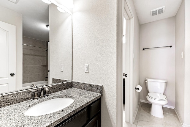 full bathroom with tile patterned flooring, vanity, tiled shower / bath combo, and toilet