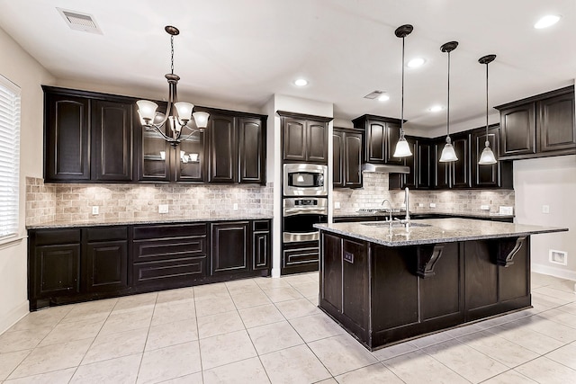 kitchen featuring pendant lighting, light stone counters, stainless steel appliances, and a chandelier