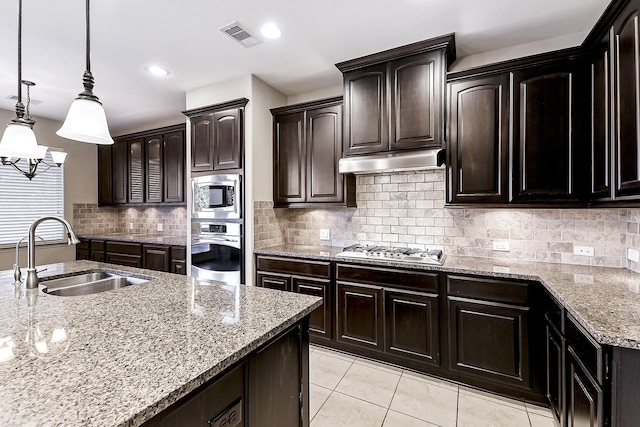 kitchen with dark brown cabinetry, sink, hanging light fixtures, stainless steel appliances, and tasteful backsplash