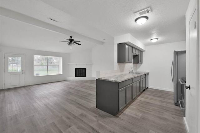 kitchen featuring decorative backsplash, light hardwood / wood-style floors, sink, and a fireplace