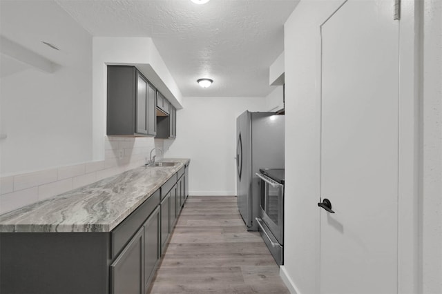 kitchen with sink, range, tasteful backsplash, a textured ceiling, and light wood-type flooring