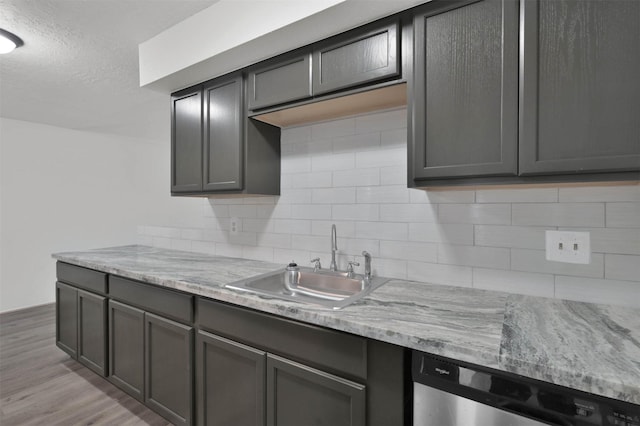 kitchen featuring dishwasher, light hardwood / wood-style floors, light stone countertops, and sink