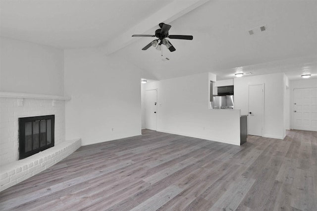 unfurnished living room with a fireplace, light wood-type flooring, lofted ceiling with beams, and ceiling fan