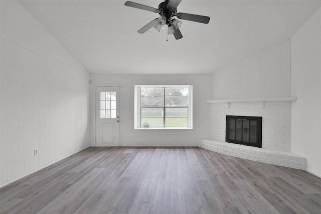 unfurnished living room featuring ceiling fan, light hardwood / wood-style flooring, lofted ceiling, and a brick fireplace