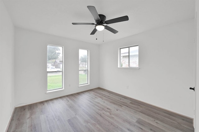 spare room with plenty of natural light, ceiling fan, and light wood-type flooring