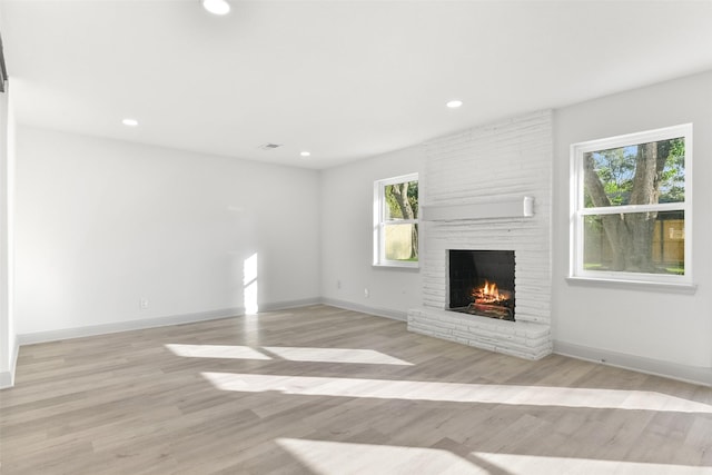 unfurnished living room with a fireplace and light hardwood / wood-style floors