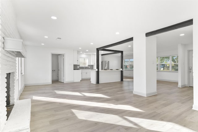 unfurnished living room with sink, a fireplace, and light wood-type flooring