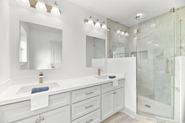 bathroom featuring a shower with door and vanity