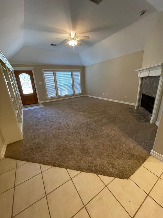 unfurnished living room featuring tile patterned floors, a tiled fireplace, ceiling fan, and vaulted ceiling