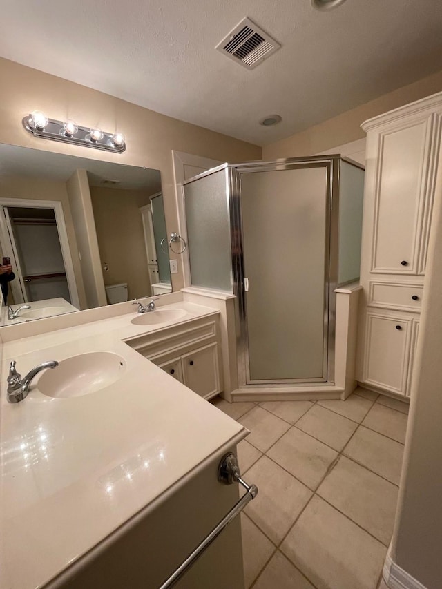 bathroom with tile patterned floors, vanity, a shower with shower door, and toilet