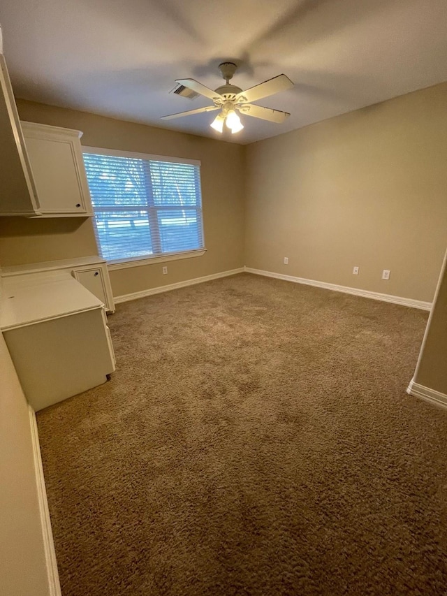 empty room with dark colored carpet and ceiling fan