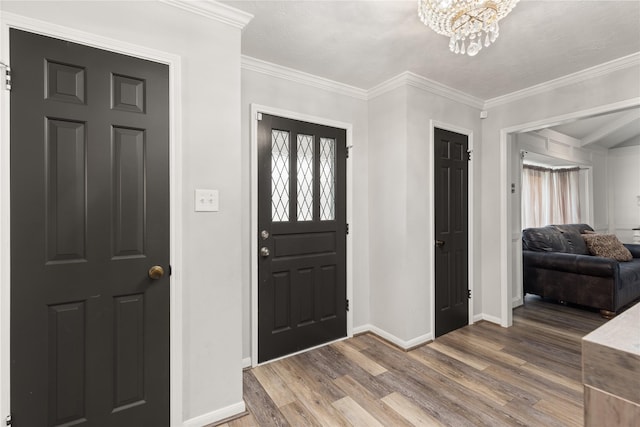 foyer entrance featuring hardwood / wood-style flooring, ornamental molding, and a chandelier