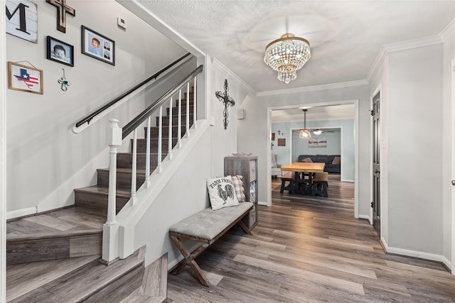 staircase with crown molding, hardwood / wood-style flooring, and an inviting chandelier