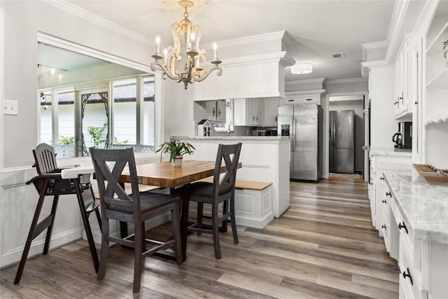 dining area with crown molding, wood-type flooring, and a notable chandelier