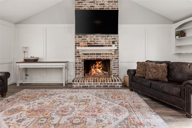 living room with built in shelves, a fireplace, hardwood / wood-style floors, and lofted ceiling