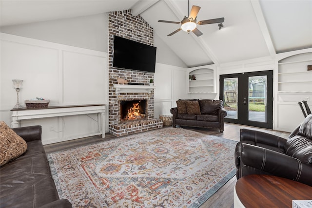 living room with a brick fireplace, lofted ceiling with beams, built in features, and ceiling fan