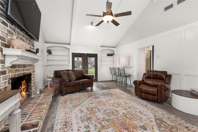 living room with built in shelves, ceiling fan, french doors, dark wood-type flooring, and a fireplace