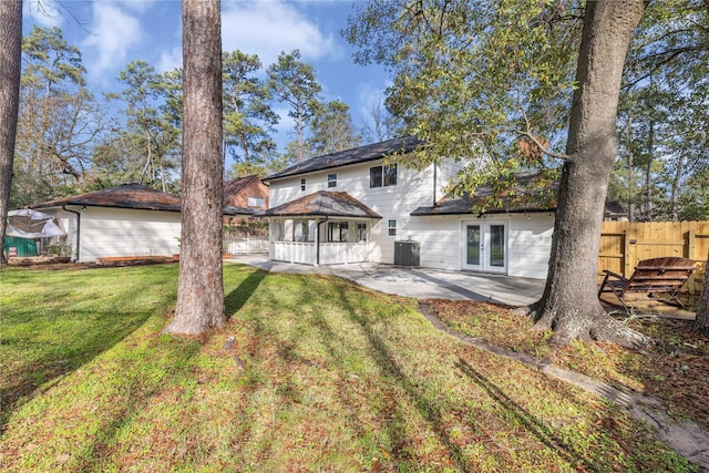 rear view of property featuring cooling unit, a yard, a patio, and french doors