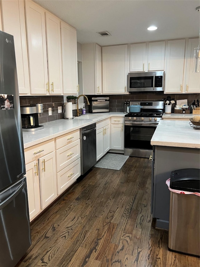 kitchen with backsplash, white cabinets, sink, dark hardwood / wood-style flooring, and stainless steel appliances