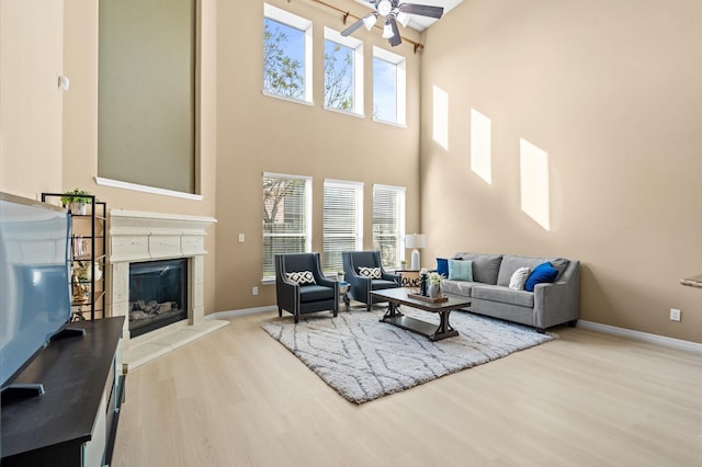 living room featuring a high ceiling, ceiling fan, and light hardwood / wood-style flooring