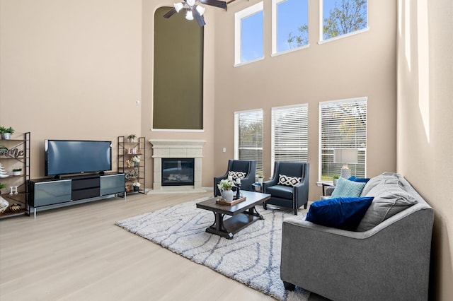 living room with a high ceiling, ceiling fan, and hardwood / wood-style flooring