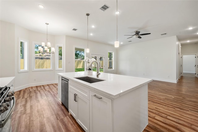 kitchen featuring sink, an island with sink, white cabinets, ceiling fan with notable chandelier, and appliances with stainless steel finishes