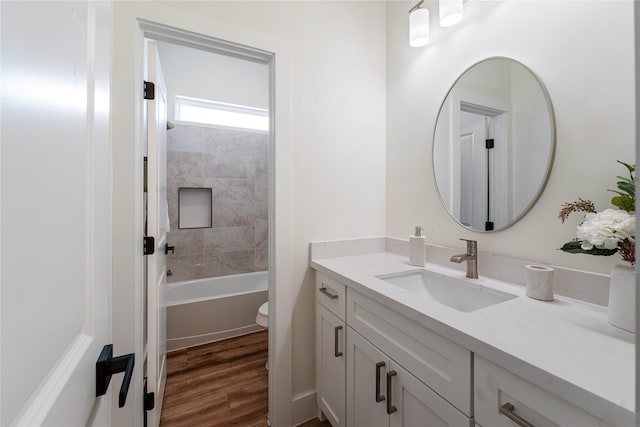 full bathroom featuring hardwood / wood-style flooring, vanity, toilet, and tiled shower / bath