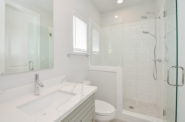 bathroom featuring vanity, toilet, and a shower with door