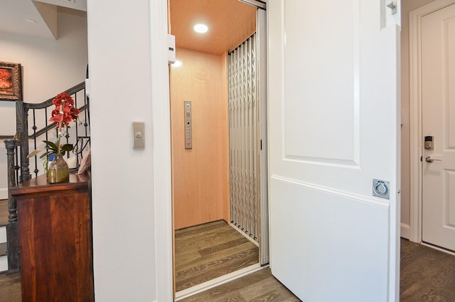 corridor featuring dark wood-type flooring and elevator