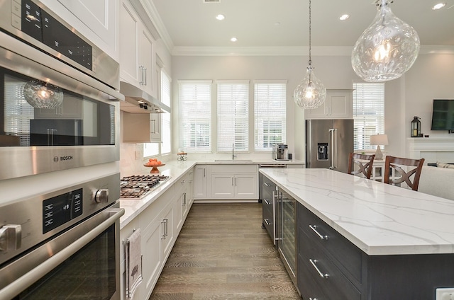 kitchen featuring white cabinetry, sink, pendant lighting, a kitchen island, and appliances with stainless steel finishes