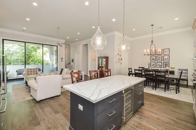 kitchen featuring dark hardwood / wood-style flooring, light stone counters, a center island, wine cooler, and hanging light fixtures