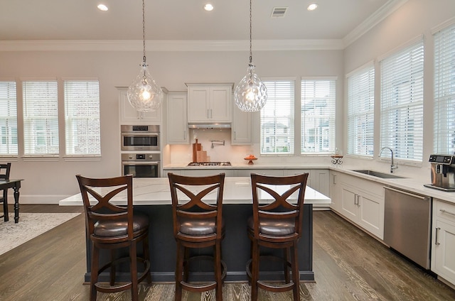 kitchen with a kitchen breakfast bar, stainless steel appliances, a kitchen island, and sink